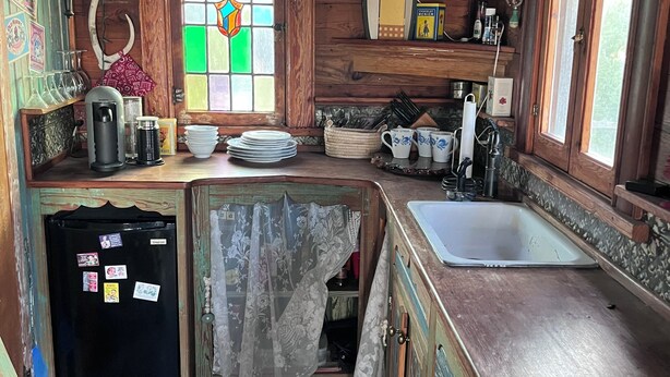 A rustic kitchen with wooden cabinets, a refrigerator, a sink, and a window with a stained glass design.