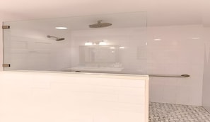 Un baño moderno con cabina de ducha de vidrio, paredes cubiertas de azulejos blancos y una zona de lavabo visible.