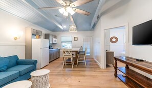 Une cuisine de taille réduite avec un coin repas, un ventilateur de plafond et un téléviseur fixé au mur.