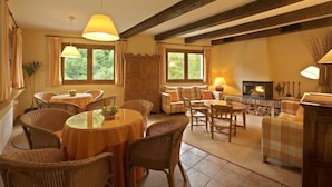 Ein gemütliches Wohnzimmer mit Kamin, Korbmöbeln und großen Fenstern.