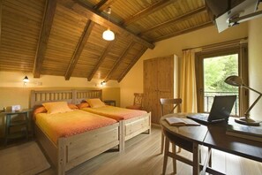A room with two wooden beds, a desk with a laptop, a chair, and a window with curtains.