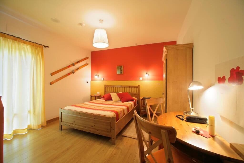 A bedroom with a bed, bedside table, lamp, and a chair.