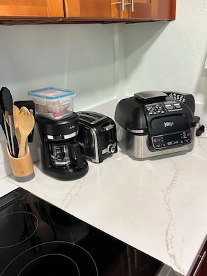 Eine Küchenarbeitsplatte mit Kaffeemaschine, Toaster und einem Ninja-Mixer.