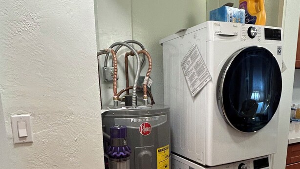 Un espace buanderie compact comprenant un lave-linge, un sèche-linge, un chauffe-eau et un aspirateur.