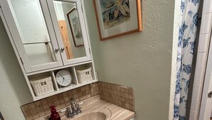 Une salle de bain avec un lavabo, un miroir et un tableau encadré au mur.