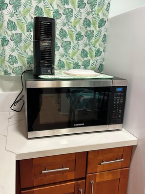 A microwave oven with a digital display and a control panel on a kitchen counter.