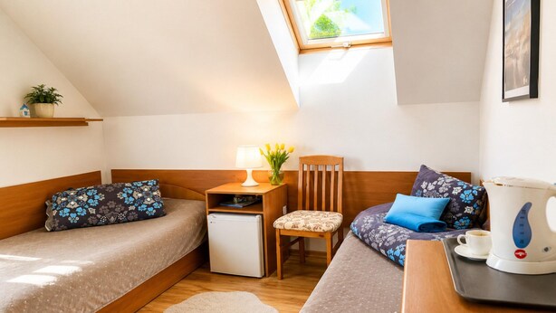 A small, cozy room with two beds, a desk, a chair, a small fridge, and a kettle. - Studio for 2 People Near the sea (Kamien Pomorski)