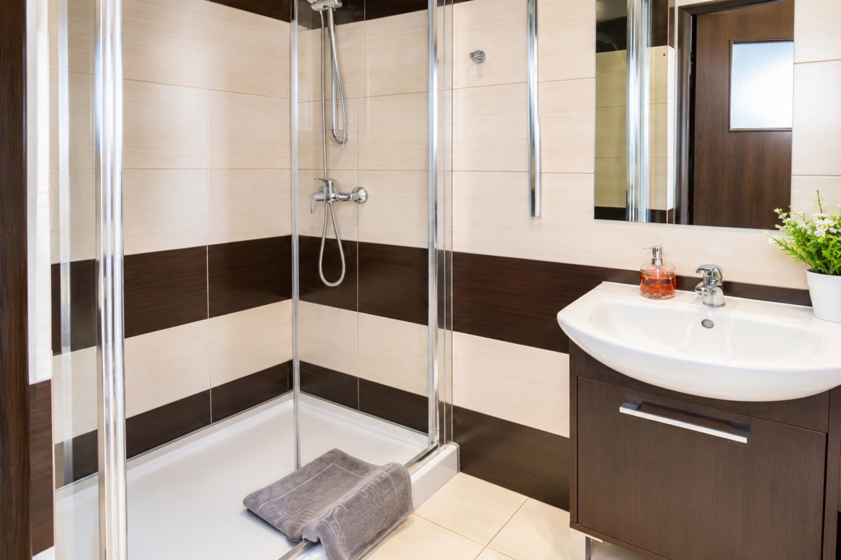 A modern bathroom with a glass shower enclosure, a white sink, and a dark wooden vanity.