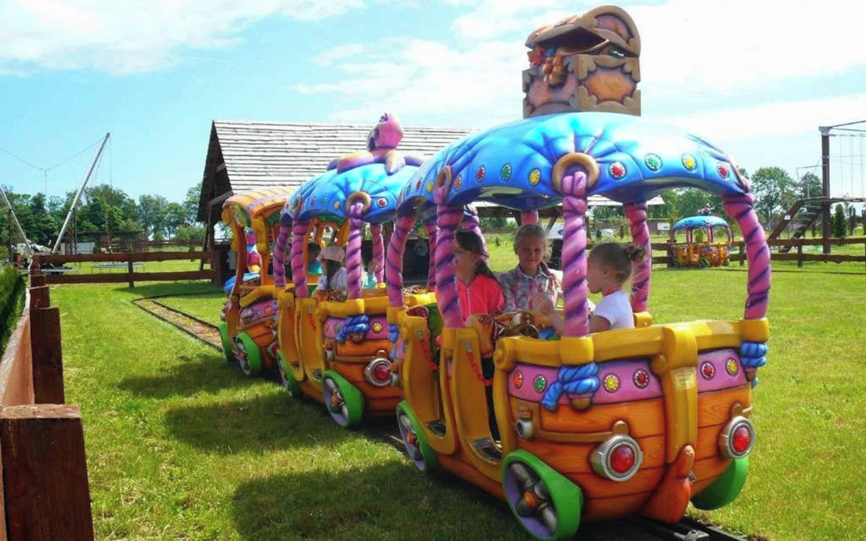 A colorful train ride with children seated inside.