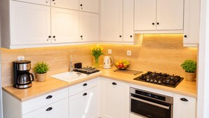 A modern kitchen with white cabinets, a built-in stove, an oven, and a coffee maker. - Studio for 2 People Near the sea (Kamien Pomorski)
