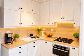 A modern kitchen with white cabinets, a built-in stove, an oven, and a coffee maker. - Studio for 2 People Near the sea (Kamien Pomorski)