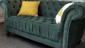 A green upholstered sofa with a yellow pillow, positioned in front of a fireplace with a decorative mantel. - Cute cottage for 8, near city centre, parking, gardens. Newly refurbished. (Edinburgh)