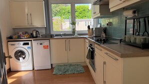 A compact kitchen with a washing machine, a sink, and a small window. - Cute cottage for 8, near city centre, parking, gardens. Newly refurbished. (Edinburgh)