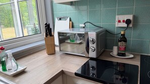 A kitchen with a toaster, a bottle of olive oil, and a window with a view of greenery.