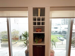 Una habitación con estantería empotrada, una planta en maceta y vistas al exterior.