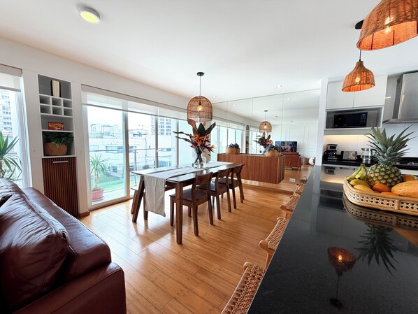 Una cocina moderna con una isla central, suelo de madera y un comedor con mesa y sillas.