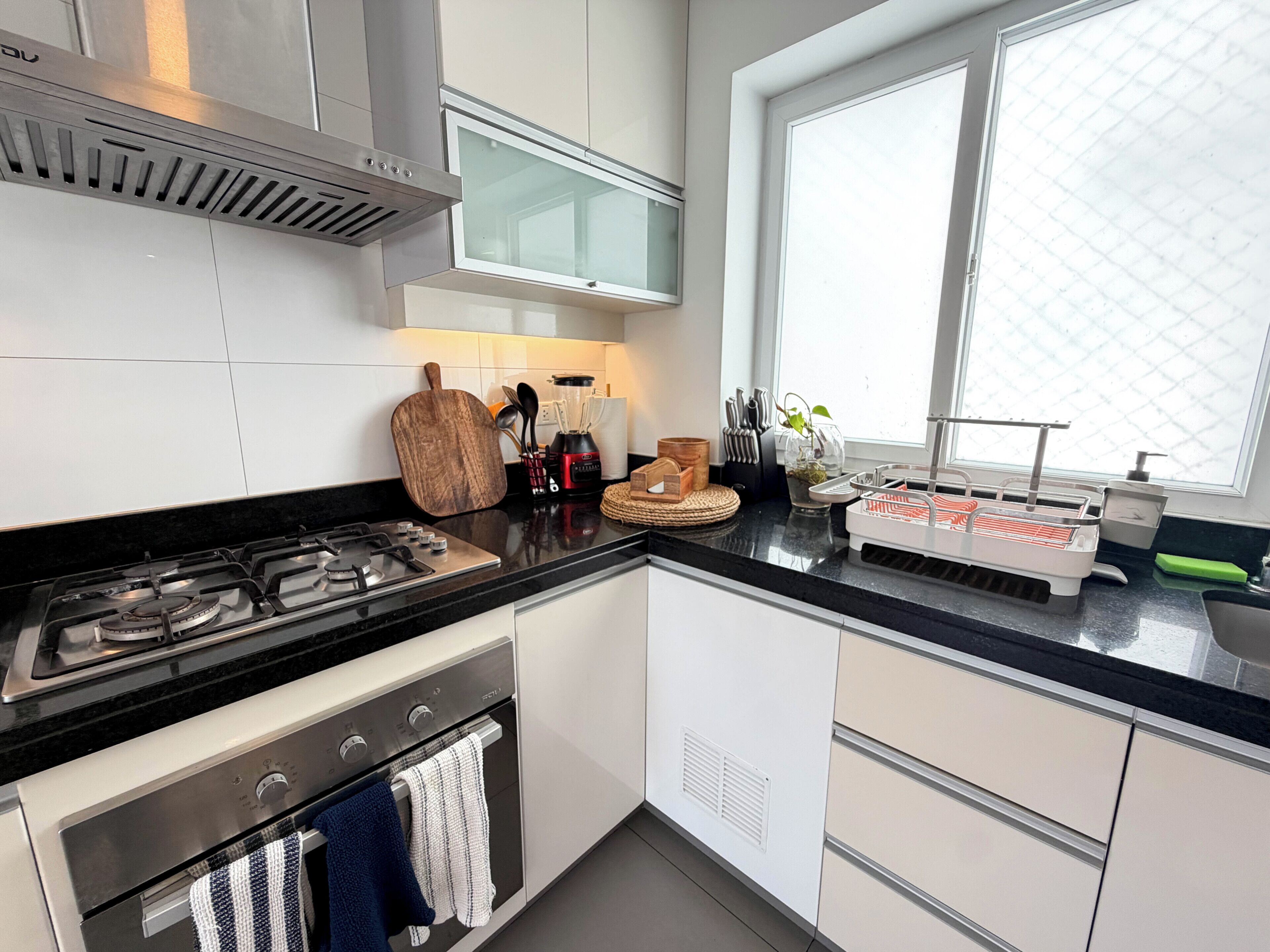 Een moderne keuken met een gasfornuis, oven en een raam dat natuurlijk licht binnenlaat.
