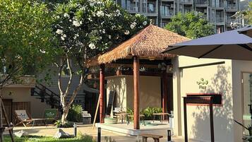 Un patio con un pabellón, asientos al aire libre y un edificio con balcones al fondo.