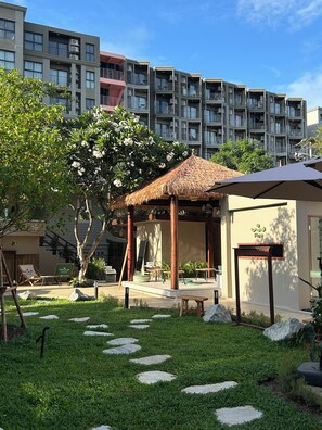 A courtyard with a gazebo, outdoor seating, and a building with balconies in the background. - Flow Hua Hin - Ice Bath and Villa (Hua Hin)
