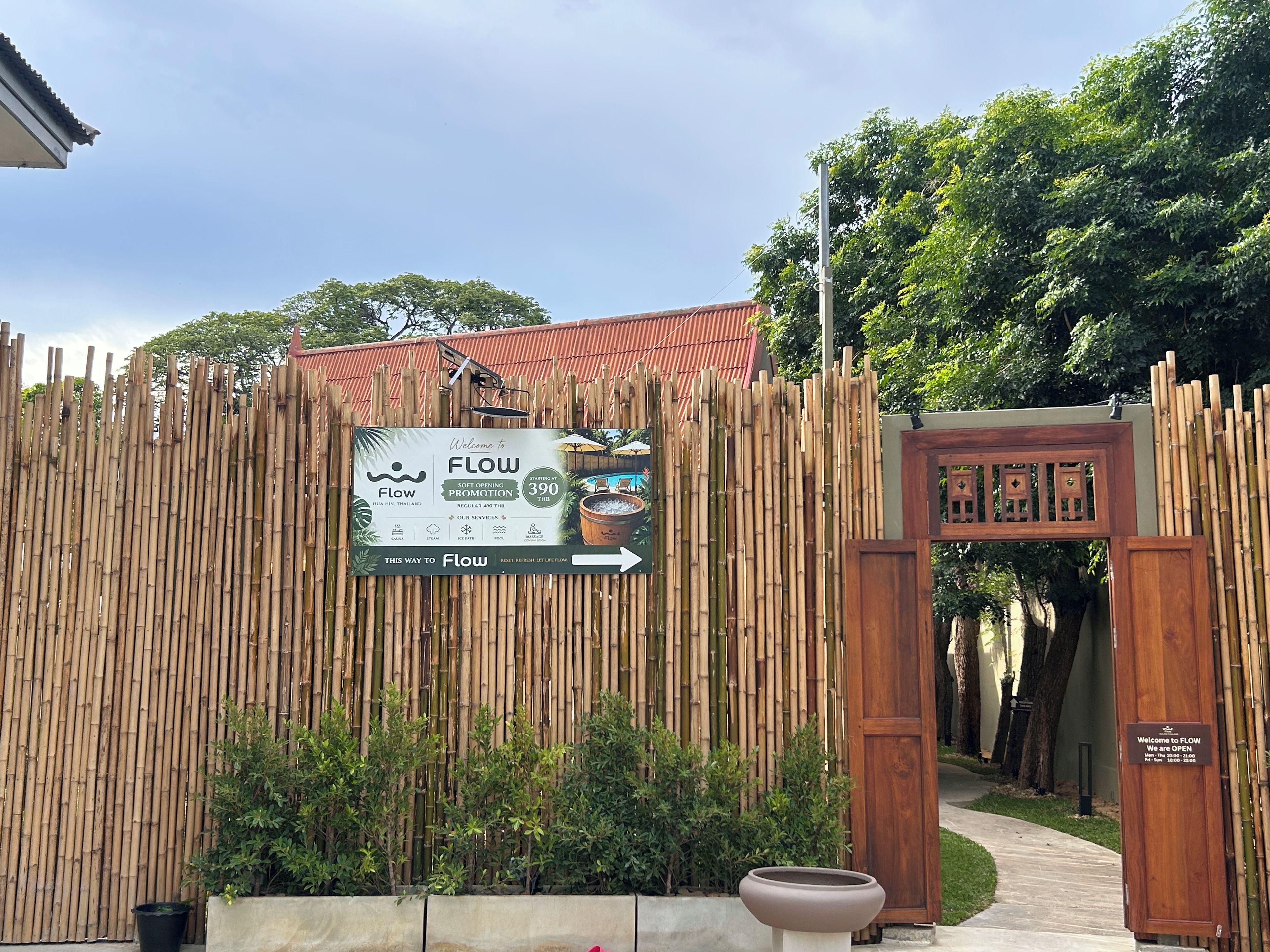 A bamboo fence with a signboard indicating the entrance to Flow, a restaurant.