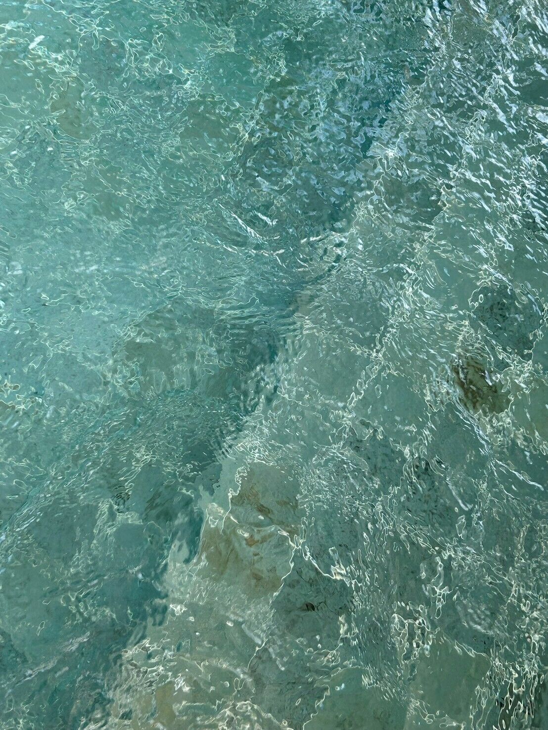 Primer plano de agua clara y poco profunda, con ondulaciones y reflejos visibles.