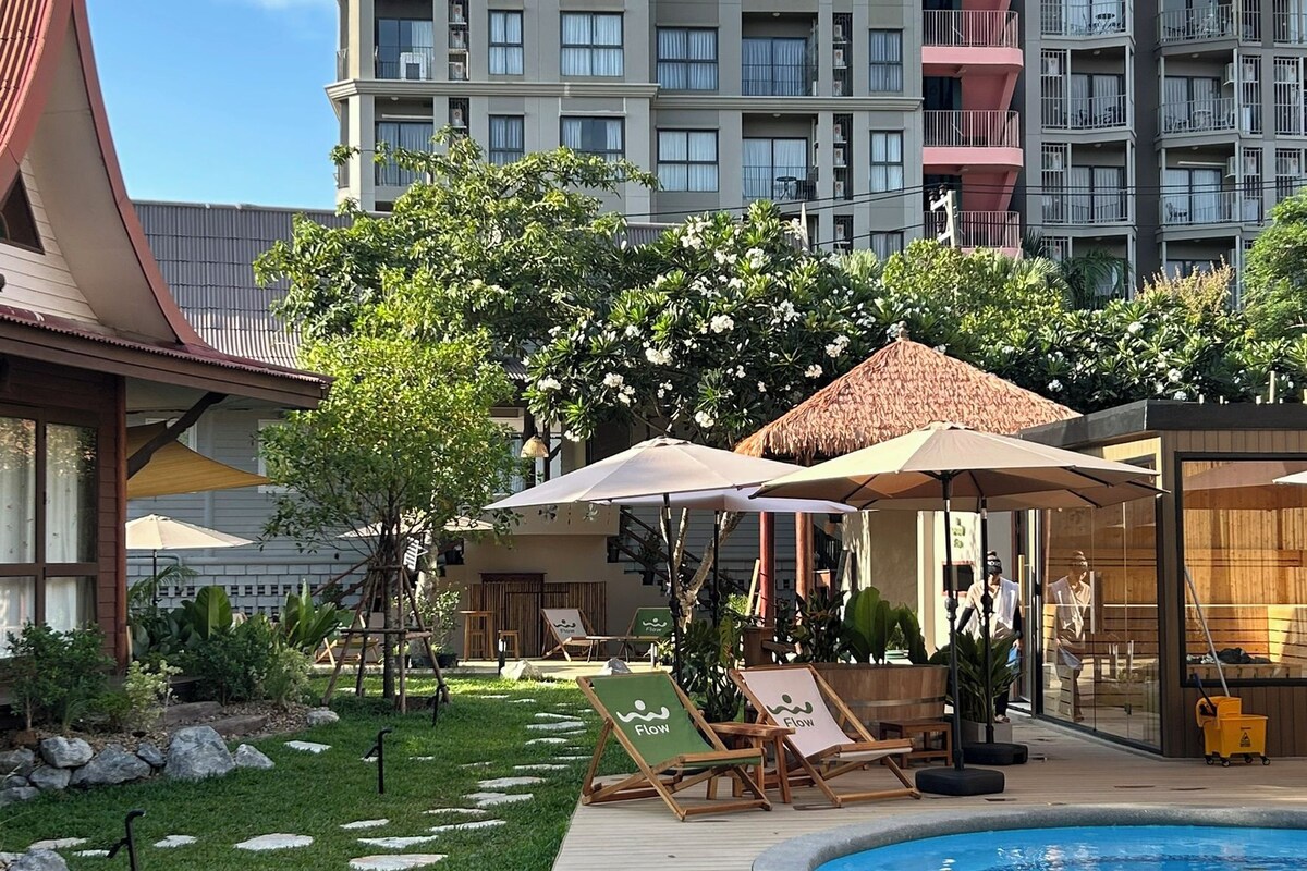 Un hotel con piscina, sillas de descanso y un jardín con piedras.