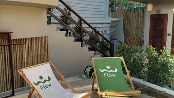 Una terraza de madera con dos sillas reclinables, una con el logotipo 'Flow' y otra con el logotipo 'Flow' y un cojín verde.