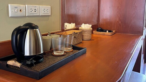 Een kitchenette met een koffiezetapparaat, bekers, glazen en een dienblad.