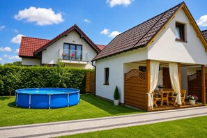A two-story house with a red-tiled roof, a visible balcony, and a swimming pool in the front yard. - Holiday Homes for 4 People Near the sea (Kamien Pomorski)