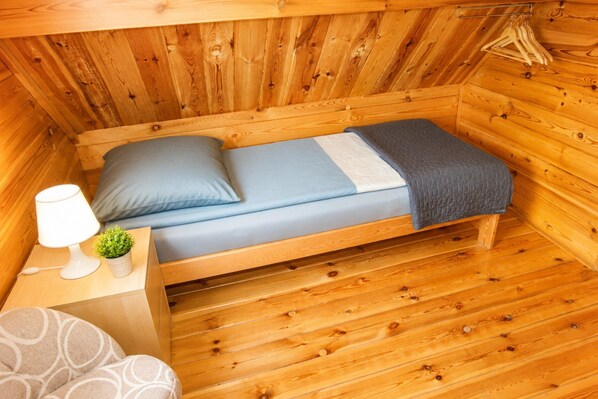 A small wooden cabin with a single bed, a bedside table with a lamp, and a small plant. - Holiday Homes for 4 People Near the sea (Kamien Pomorski)