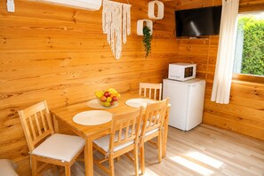 A wooden interior with a dining table, chairs, a microwave, and a television. - Holiday Homes for 4 People Near the sea (Kamien Pomorski)