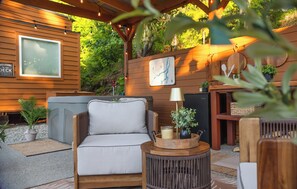 Un espacio al aire libre acogedor con un sofá, una mesita auxiliar y una pérgola de madera.