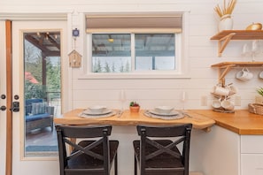 A dining area with a wooden table, two chairs, and a window above.
