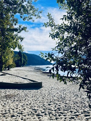 Una playa con cielo despejado, árboles y un mar tranquilo al fondo.