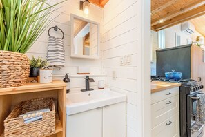 Una cocina moderna con armarios blancos, una estufa negra y una ventana sobre el fregadero.