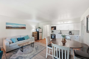A compact living space with a kitchenette, a dining area, and a sofa with cushions. - Cozy Condo by Downtown (Bend)