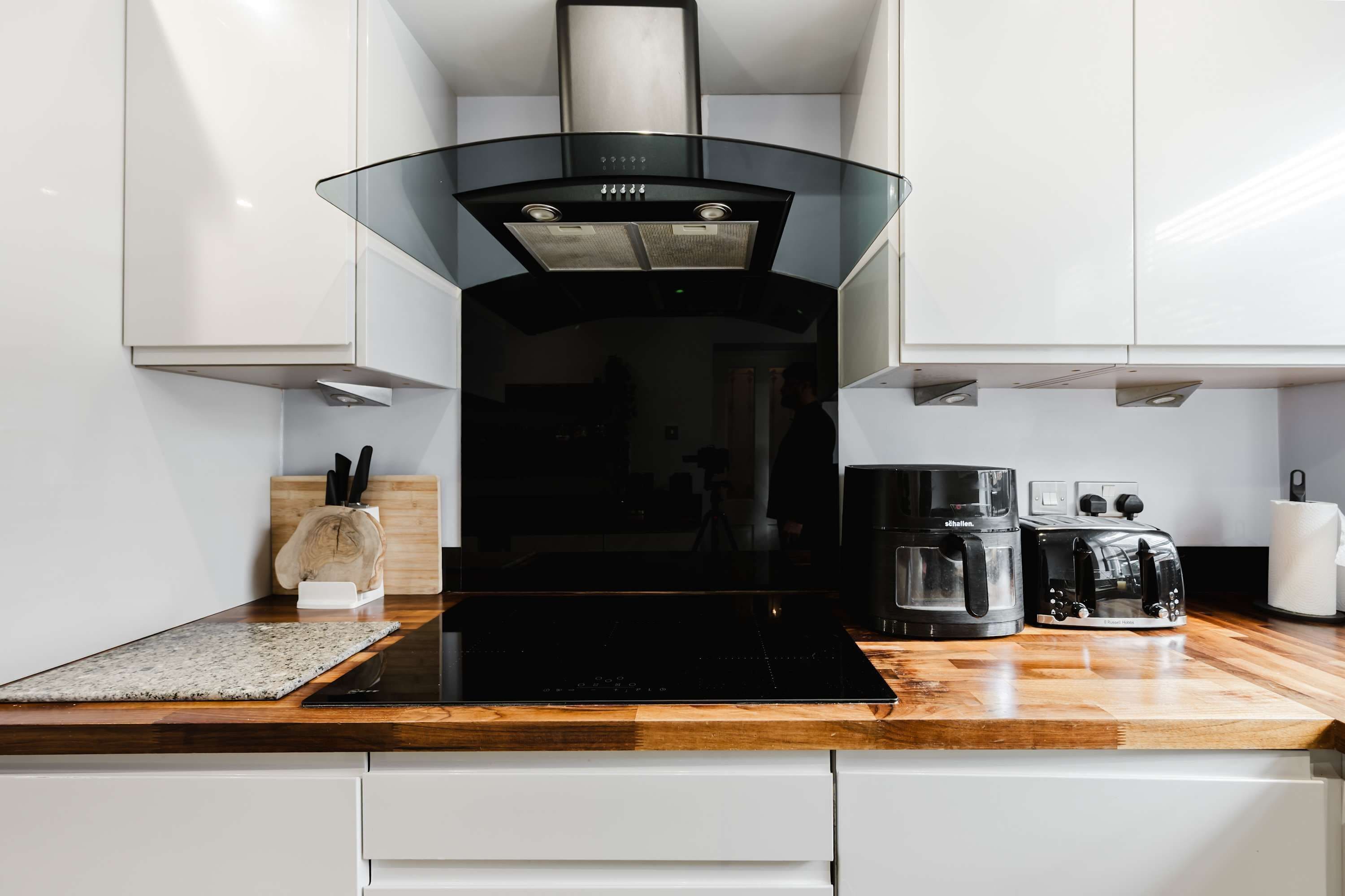 A modern kitchen with a black induction cooktop, a coffee maker, and a toaster on the countertop.