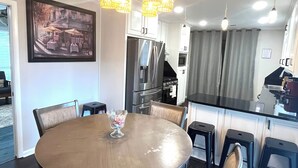 Ein Essbereich mit einem runden Tisch, Stühlen, einer Chandelier und einer Küche im Hintergrund.