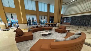 A spacious lobby with a curved seating area, large windows, and a marble floor. - Wanlin Yijing Holiday Hotel (Foshan)