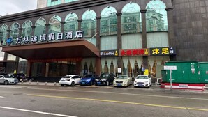A hotel with a modern facade, multiple parking spaces, and a prominent signage for a coffee shop. - Wanlin Yijing Holiday Hotel (Foshan)