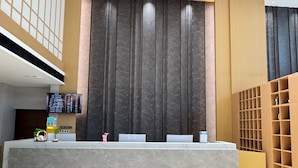 A reception desk with a digital display, a plant, and a pink sculpture. - Wanlin Yijing Holiday Hotel (Foshan)