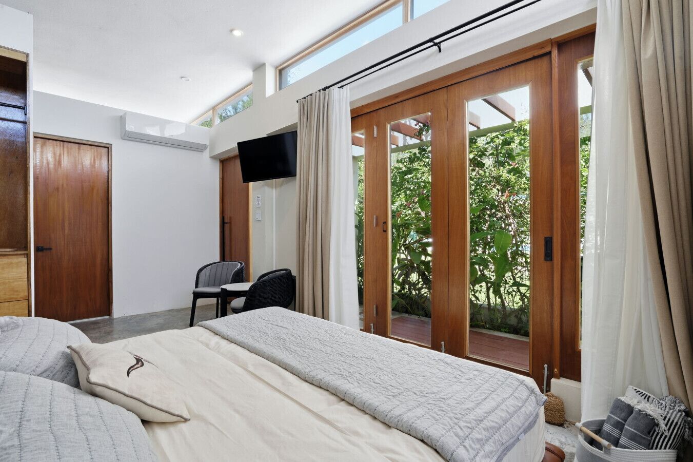 A hotel room with a bed, a desk, a chair, a TV, and a sliding glass door leading to an outdoor area.