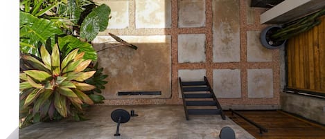 A modern interior with a concrete floor, a wooden staircase, and a large potted plant.