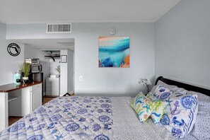 A bedroom with a bed, a desk, a coffee maker, and a painting on the wall. - New Listing -Cozy Suite room w/blacony City-View at Ocean Manor Resort (Fort Lauderdale)