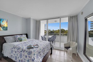A hotel room with a bed, a balcony with a table and chairs, and a view of the outdoors. - New Listing -Cozy Suite room w/blacony City-View at Ocean Manor Resort (Fort Lauderdale)