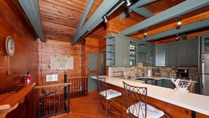 A wooden interior with a kitchen area, bar stools, and a clock on the wall. - Sunsky at Skyforest - 3bdr (Skyforest)