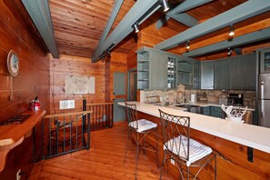 Ein Holzinterieur mit Küchenzeile, Barhocker und einer Wanduhr.
