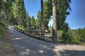 A paved path leading to a stone building with a green roof, surrounded by tall trees. - Sunsky at Skyforest - 3bdr (Skyforest)