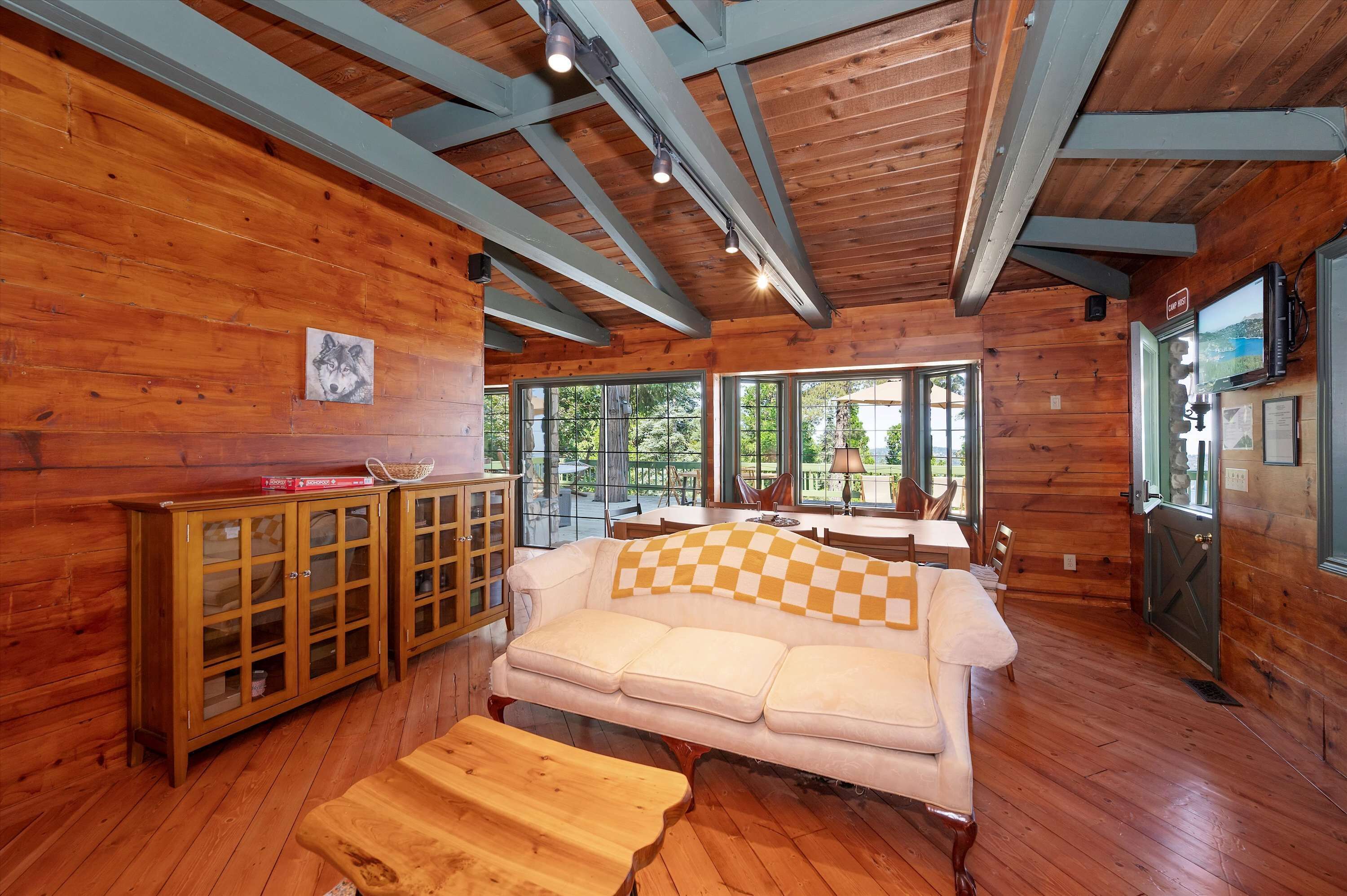 A cozy cabin interior with a wooden floor, a sofa, a wooden cabinet, and a television.