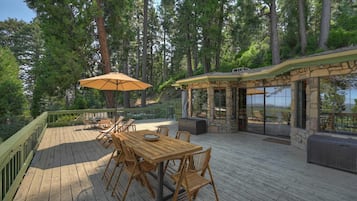 A wooden deck with a table and chairs, surrounded by trees.
